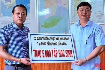 Chủ tịch Ủy ban nhân dân huyện Đầm Dơi (bìa phải) tiếp nhận 5.000 tập hỗ trợ từ Cơ quan Thường trực Báo Nhân Dân tại vùng đồng bằng sông Cửu Long.
