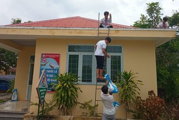 Học sinh tại Quảng Bình tham gia chèn mái tôn trường học để hạn chế thiệt hại do gió bão. 