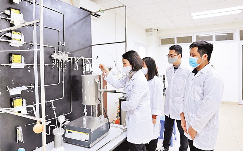 GS,TS Lê Minh Thắng cùng các cộng sự trong phòng thí nghiệm bên sơ đồ công nghệ xử lý khí thải. Ảnh: Ngô Hà