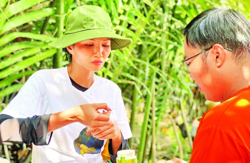 Anh Phan Minh Tiến (bên phải) giới thiệu đến du khách sản phẩm đường làm từ mật dừa nước.