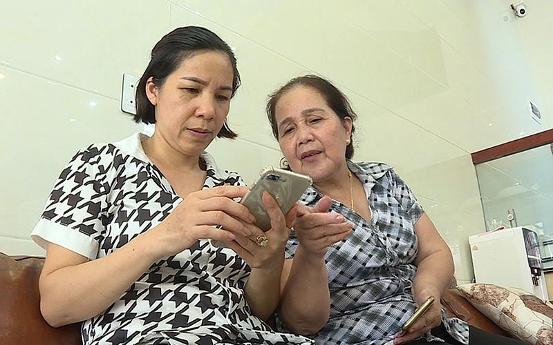 Thành viên tổ công nghệ số cộng đồng ở xã Ðông Xá (huyện Vân Ðồn, tỉnh Quảng Ninh) hướng dẫn người dân cài đặt các ứng dụng thông tin trên điện thoại. (Ảnh NGUYỄN DUY) 