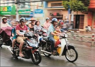 Phụ huynh chở hai cháu không đội mũ bảo hiểm trên đường Quang Trung.